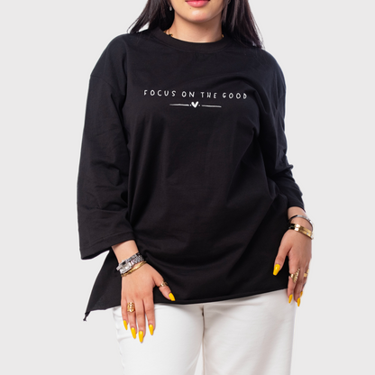 Person wearing a black long-sleeve shirt with 'Focus on the Good' text on a beige background